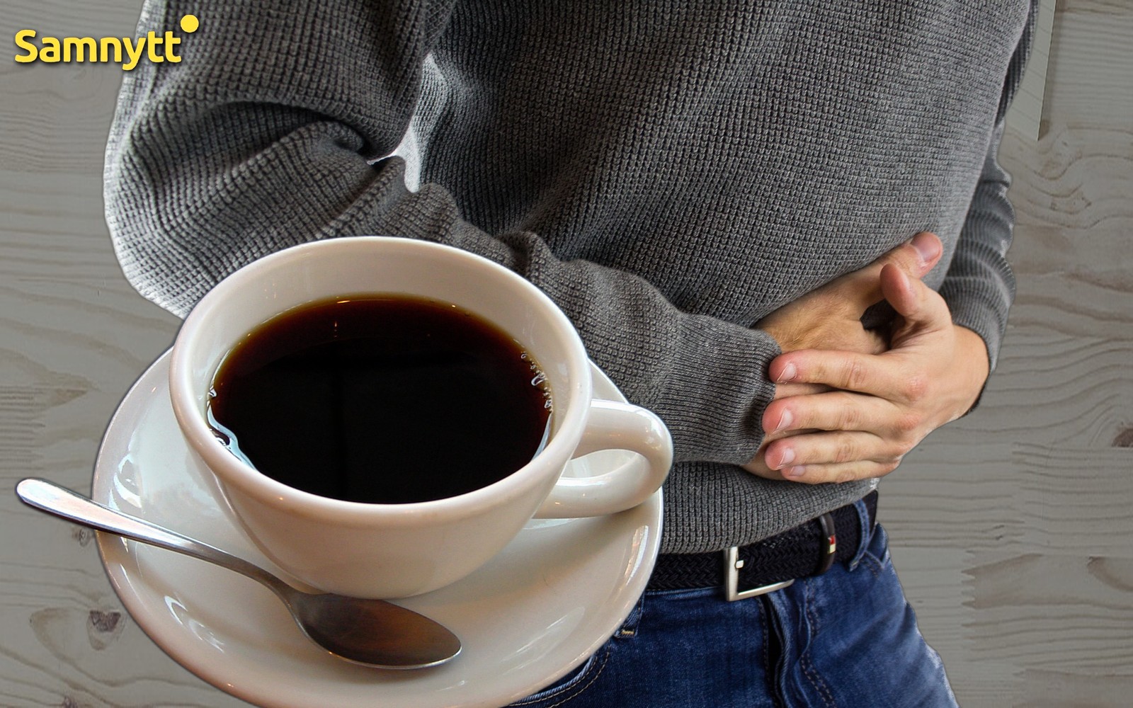 Man som håller sig om magen vid en kopp kaffe